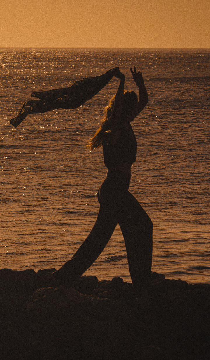 ba&sh sustainable collection. Image of a woman stretching at sunrise