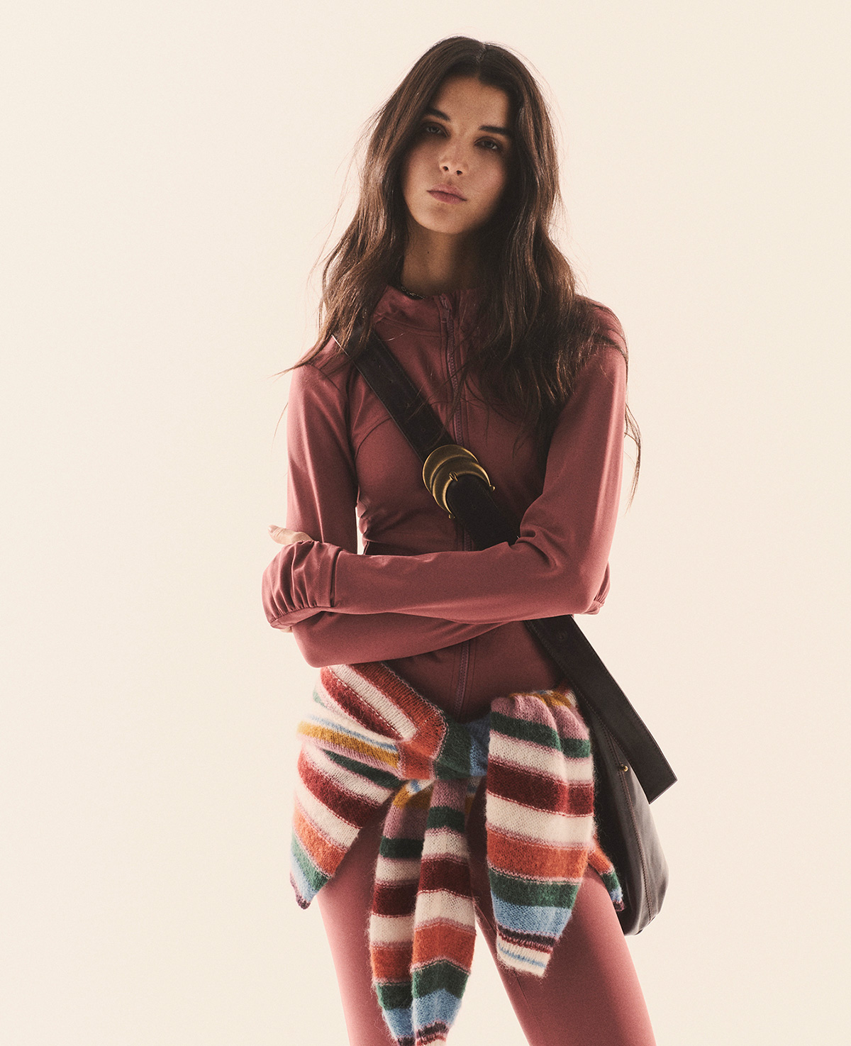Brunette model wearing a pink sports outfit, a ba&sh jumper, the Youyou bag and ankle boots