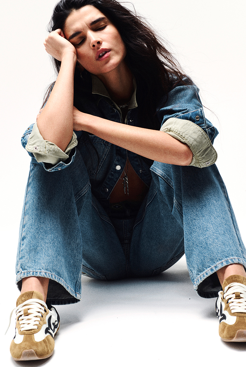 a model sitting on the floor wearing jeans and a denim shirt 