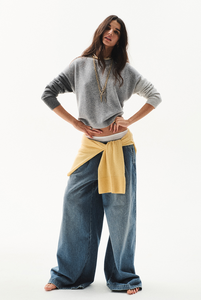 a model wearing a jacket and wide blue jeans
