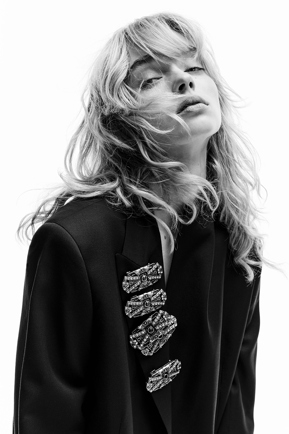 A model wearing black blazer and jewelry